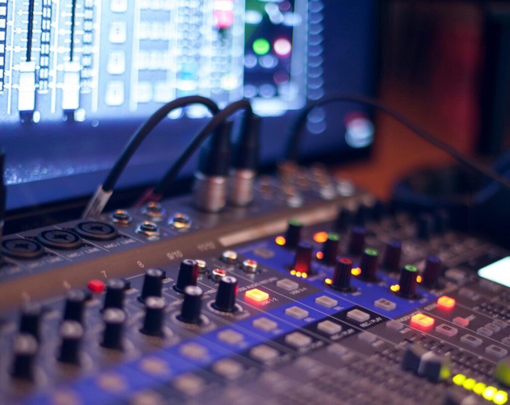 Close-up of a professional audio mixing console with glowing LED indicators.